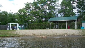 Une zone de plage sablonneuse avec un pavillon abrité et une balançoire.