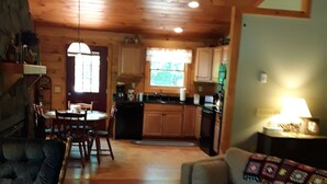 Un intérieur de chalet chaleureux comprenant un coin repas, une cuisine et un salon.