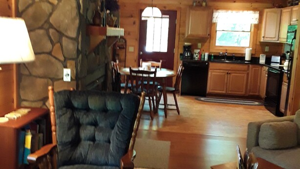 Un intérieur chaleureux avec une cheminée en pierre, une table à manger en bois et un coin salon confortable.