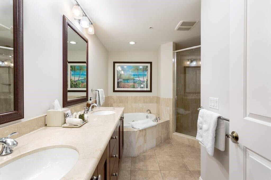 A modern bathroom with two sinks, a bathtub, a shower, and a large mirror.