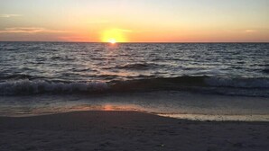 A beach at sunset with waves gently lapping the shore. - Bay Bungalow at Naples Bay Resort (Naples)
