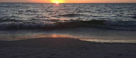 Una platja al capvespre amb ones que brollen suaument a la riba.