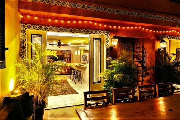 An indoor dining area with a wooden table, chairs, and potted plants.