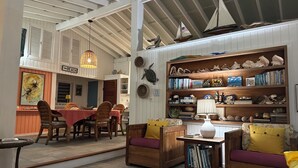 Ein gemütliches Zimmer mit Essbereich, Bücherregal und einem kleinen Modell eines Segelbootes.