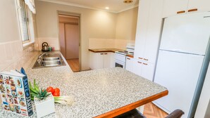Une cuisine dotée de plans de travail en granit, d’armoires blanches, d’une cuisinière et d’un réfrigérateur.