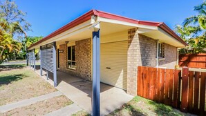 Une maison de plain-pied avec une façade en briques, un toit rouge et une porte de garage.