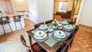 Un coin repas avec une table en bois dressée pour six personnes, entourée de chaises.