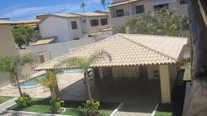 A residential area with a swimming pool, a covered patio, and a lawn.