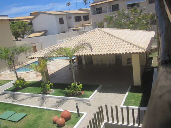 A residential area with a swimming pool, a covered patio, and a lawn.