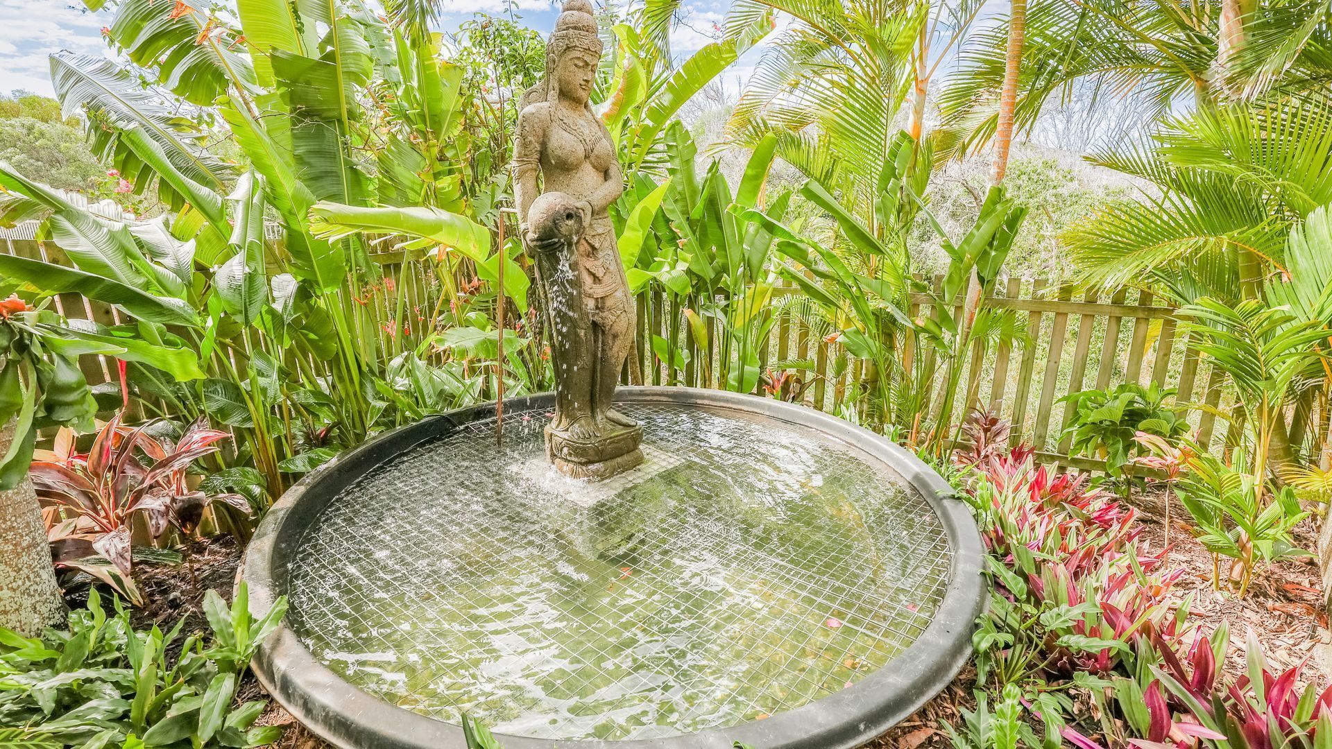 En stenstatue i en have med et cirkulært vandbassin.