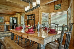 Un intérieur en bois avec une table à manger dressée pour six personnes, entourée de chaises rustiques.