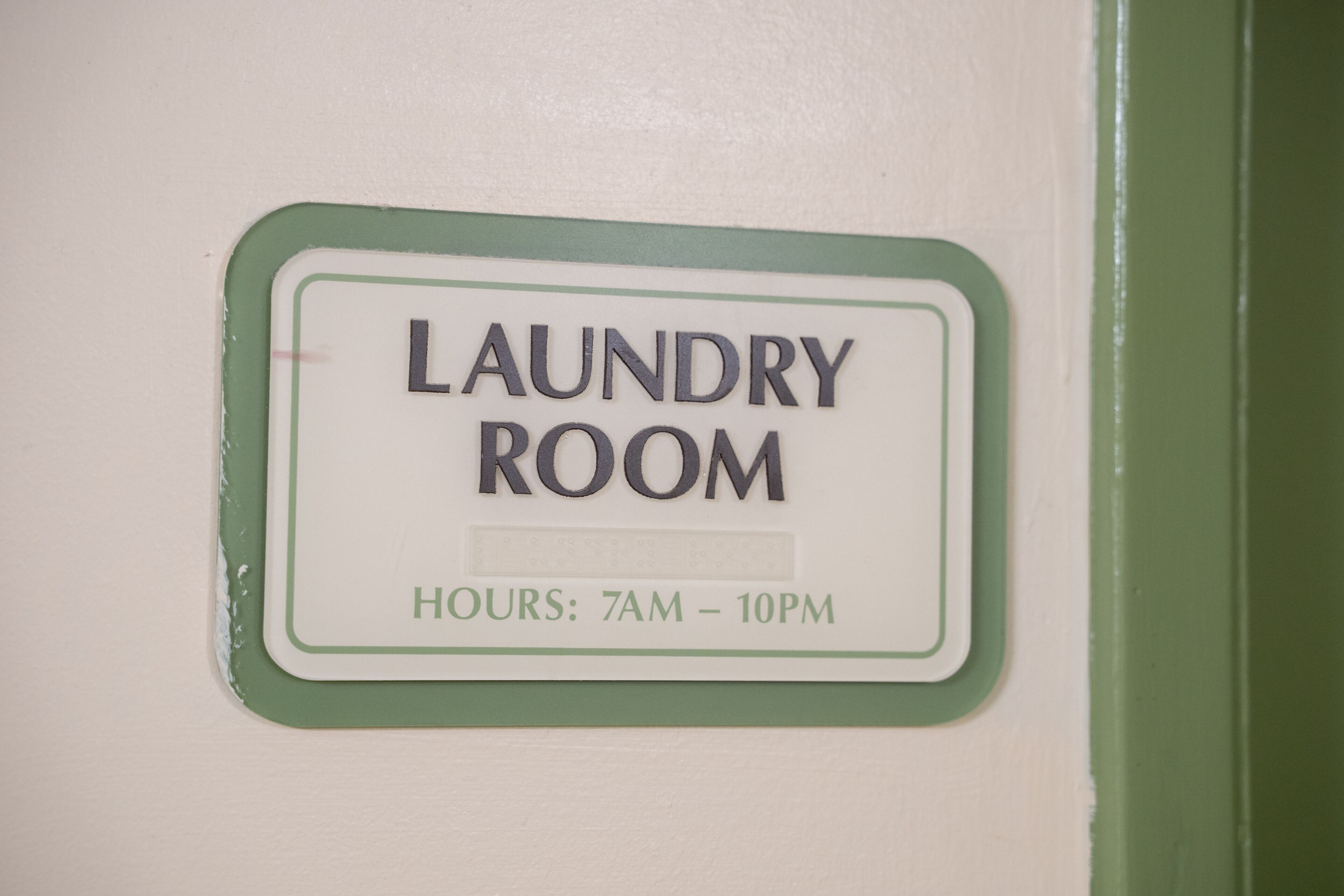 A sign indicating a laundry room with operating hours from 7 AM to 10 PM.