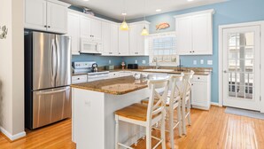 A modern kitchen with white cabinets, stainless steel appliances, and a granite countertop. - Rare private beach side location that also has beautiful bayside views (Bethany Beach)