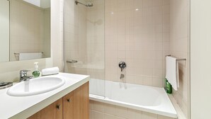 A modern bathroom with a bathtub, a sink, and a shower. - Apartment 2 Kalimna (Lorne)