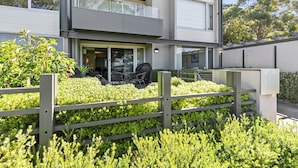 A modern building with a flat roof, large windows, and a covered outdoor seating area. - Apartment 2 Kalimna (Lorne)
