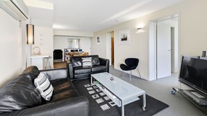 Een moderne woonkamer met een leren bank, een glazen salontafel en een flatscreen televisie.