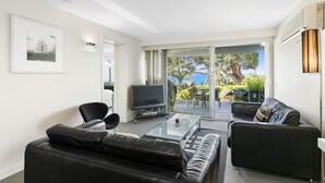 Een moderne woonkamer met een flatscreen televisie, leren banken en een glazen salontafel.