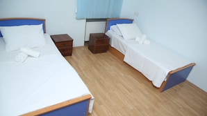 Una habitació amb dos llits individuals, taules de nit de fusta i un radiador.