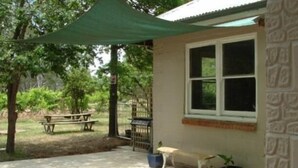 A covered patio area with a bench, a potted plant, and a window. - The Grove Gunbower.. (Gunbower)