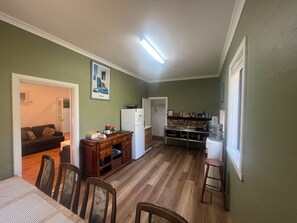 A compact living space with a dining area, kitchen, and a door leading to another room.