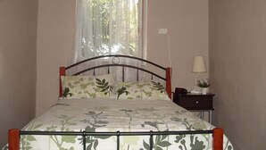 A bedroom with a bed, a window with sheer curtains, a bedside table with a lamp, and a wall socket. - The Grove Gunbower.. (Gunbower)
