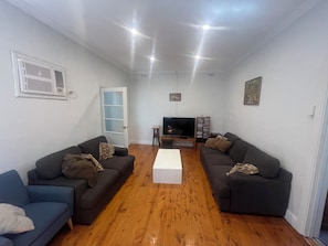 A living room with two sofas, a coffee table, a TV, and a bookshelf. - The Grove Gunbower.. (Gunbower)