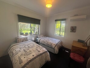 A bedroom with two beds, a desk, and a window with a view of greenery. - The Grove Gunbower.. (Gunbower)