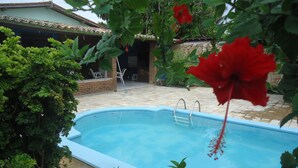 Piscina rodeada por vegetação exuberante e uma parede de tijolos.