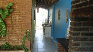 Um corredor estreito com chão de azulejos, paredes de tijolo e uma parte pintada de azul.