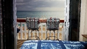 A balcony with two chairs facing the sea.