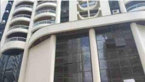 A modern building with a curved facade, large windows, and a covered entrance area. - Mi's Apartment - 2 minutes from Pitangueiras Beach - Guarujá (Guarujá)