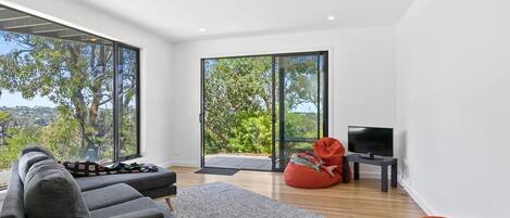 A modern living room with a sofa, bean bag, and a television on a small table.
