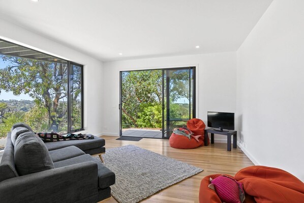 A modern living room with a sofa, bean bag, and a television on a small table.