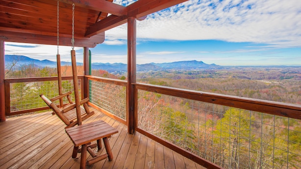A wooden deck with a swing chair and a table, overlooking a mountainous landscape. - 🏔️ A Starr Peak View🌲 Resort Pool, Hot Tub & Game Room (Sevierville)
