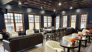 Un restaurante con una decoración moderna, con una combinación de asientos de cuero y tela, ventanas amplias y suelo de madera.