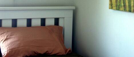 A bedroom with a bed, a wall-mounted lamp, and a painting.