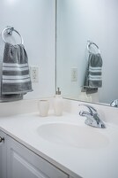 A bathroom with a white sink, a mirror, and two towels hanging on towel rings.