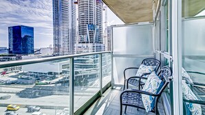 Un balcon offrant une vue sur le paysage urbain, avec de hauts immeubles et une étendue d’eau.