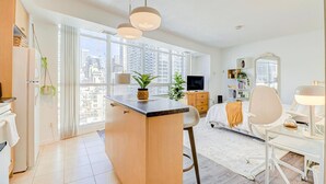 Un appartement moderne doté d’une cuisine, d’un coin repas et d’une grande fenêtre offrant une vue sur la ville.