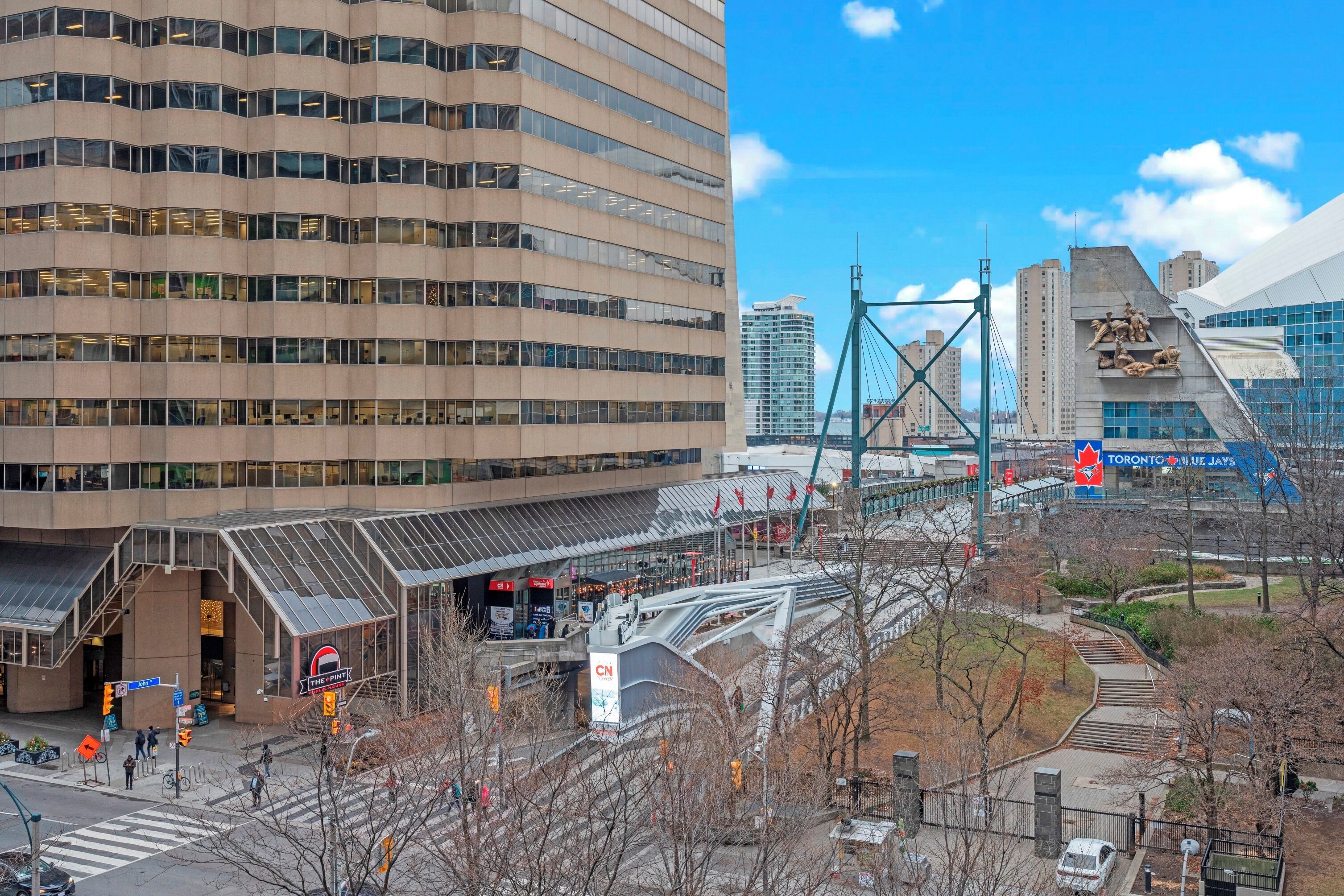 Um edifício moderno com fachada de vidro, entrada imponente e uma estrutura de ponte nas proximidades.