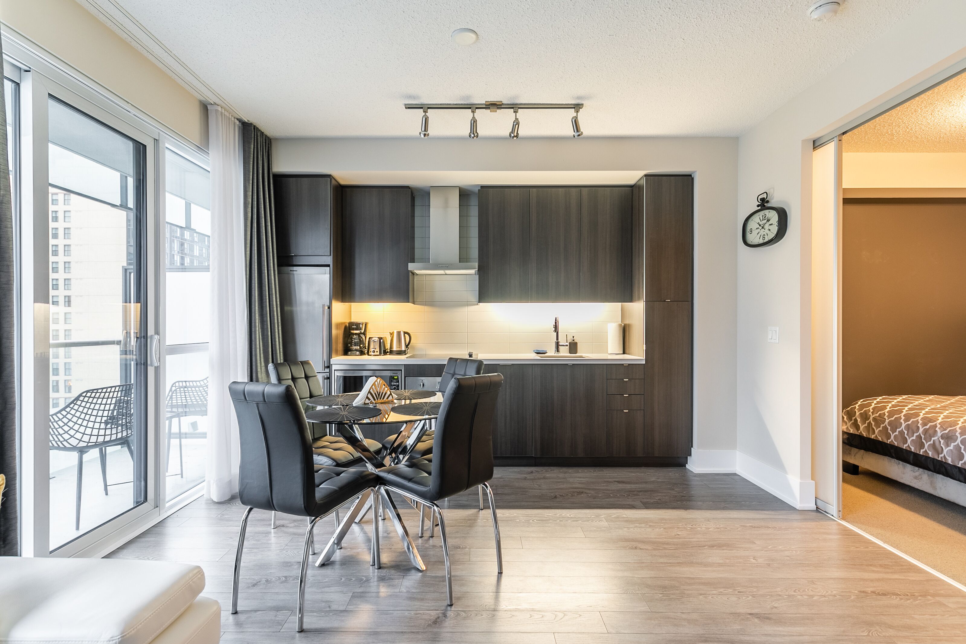 A modern apartment with a dining area, kitchen, and a bedroom.