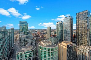 A high-rise urban area with modern skyscrapers, a clear sky, and a busy street. - Modern Downtown Apartments (Toronto)
