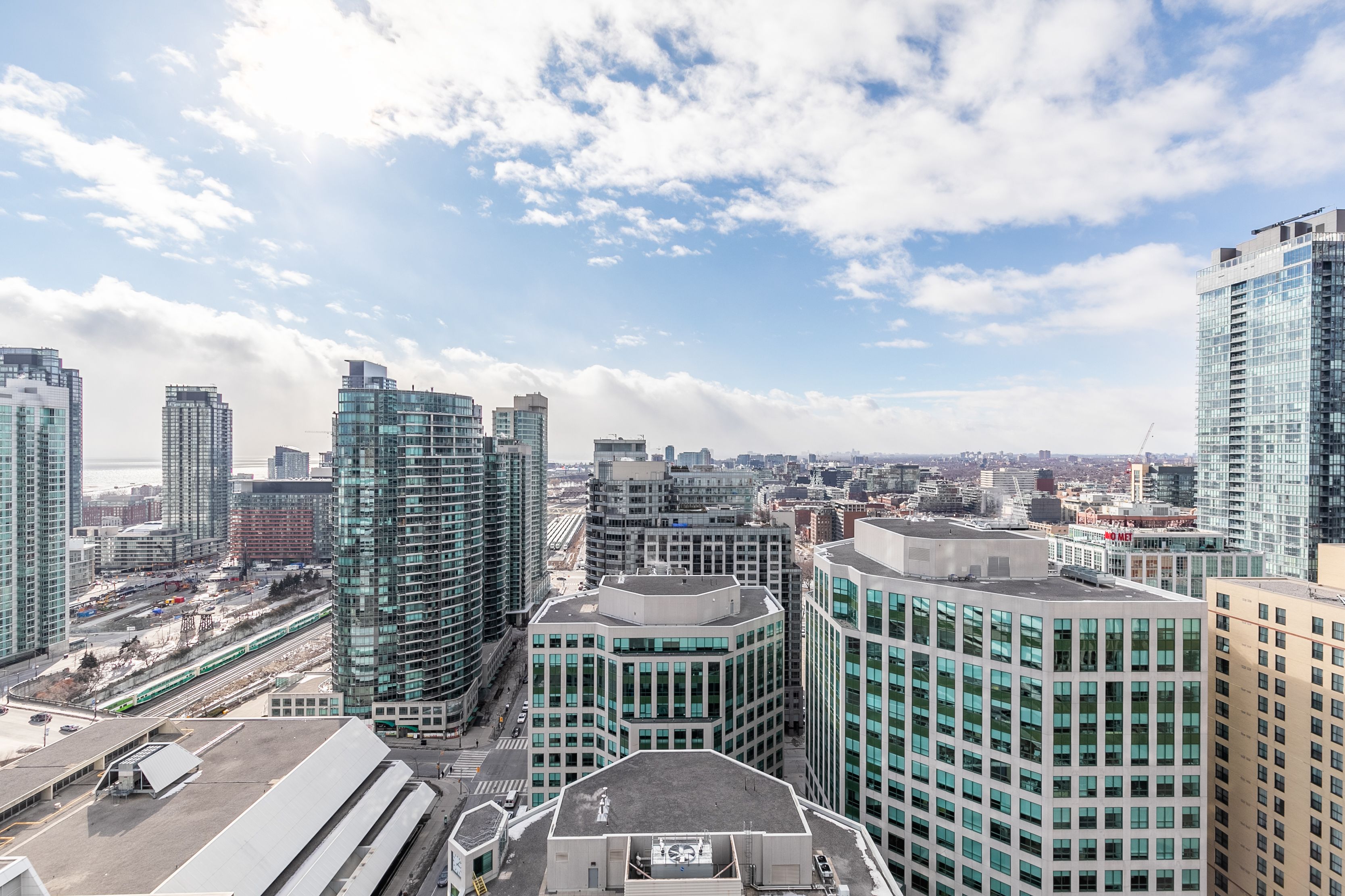 A high-rise urban area with modern buildings, a train track, and a clear sky.