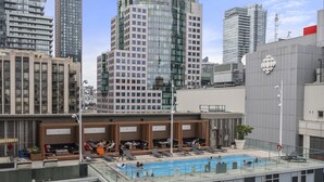 A rooftop pool with lounge chairs and a seating area, surrounded by high-rise buildings. - Modern Downtown Apartments (Toronto)