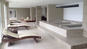 Un área de spa con múltiples sillones de descanso y una bañera de hidromasaje central.