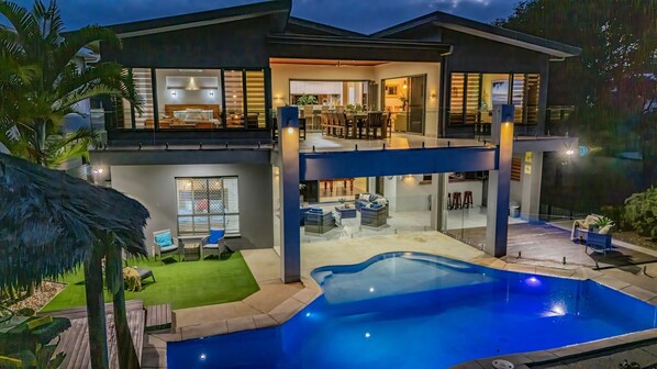 Une maison moderne à deux étages, dotée d’une piscine, d’un patio couvert et d’un jardin bien entretenu.
