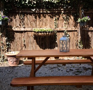 A wooden picnic table with a lantern and hanging planters against a wooden fence. - The Nest Hudson (Hudson)