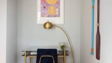 Quarto com uma mesa, uma obra de arte emoldurada, uma toalha azul e dois pranchas de remo na parede.