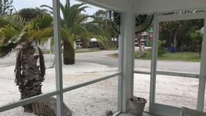 A room with large windows, a palm tree, and a view of a street. - Enjoy a Fun in the Sun getaway 3 Bedroom House, Tiki Hut, Boat Ramp, & Dockage! (Key Largo)