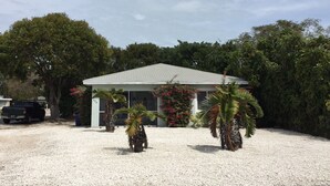 A house with a white exterior, a tiled roof, and a gravel driveway. - Enjoy a Fun in the Sun getaway 3 Bedroom House, Tiki Hut, Boat Ramp, & Dockage! (Key Largo)